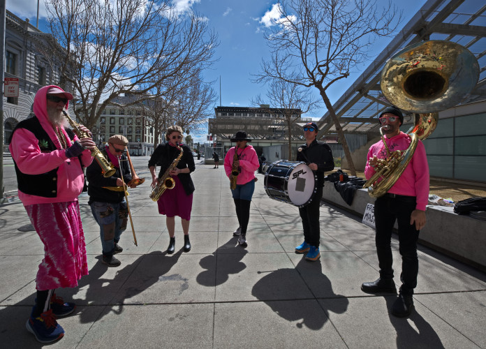 band in pink play sax, tuba, trumpets